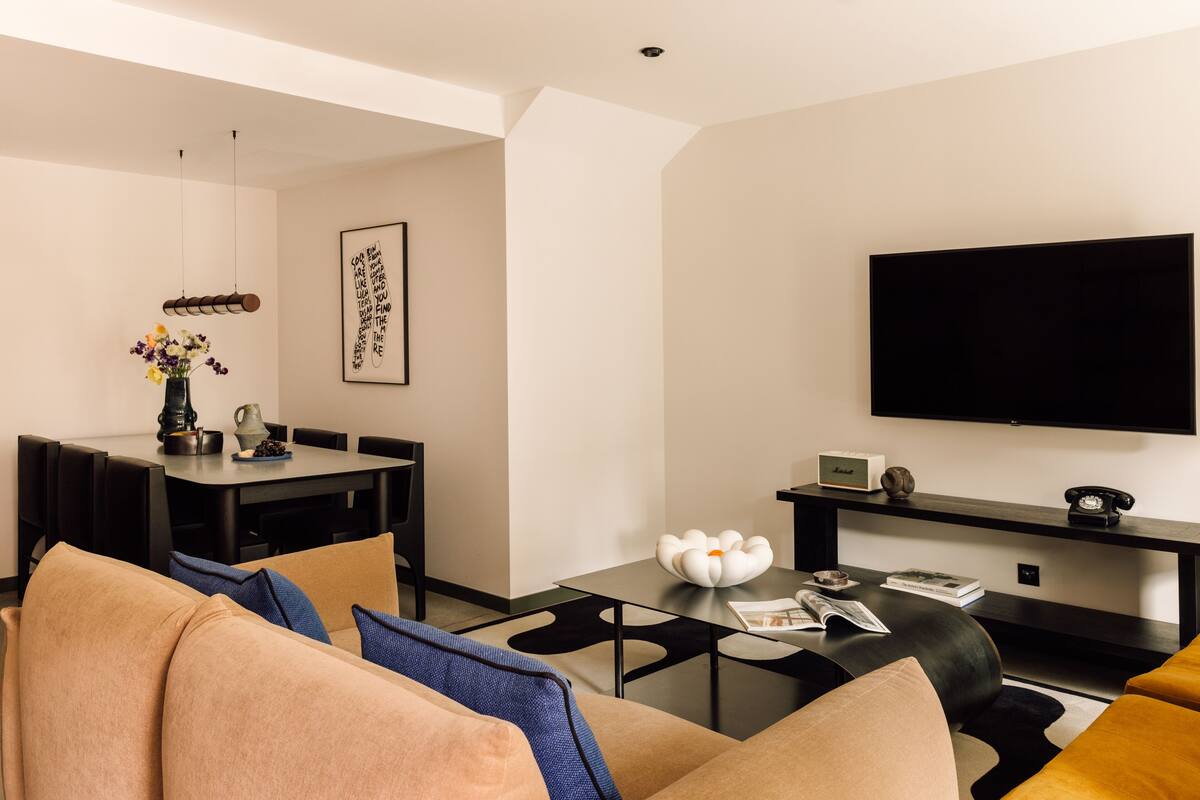 A modern living room with a sofa, coffee table, and a flat-screen TV mounted on the wall.