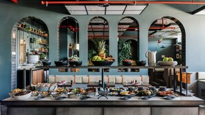 A buffet setup with various food items and a seating area with a bench. - The Rebello Hotel & Spa (Vila Nova de Gaia)