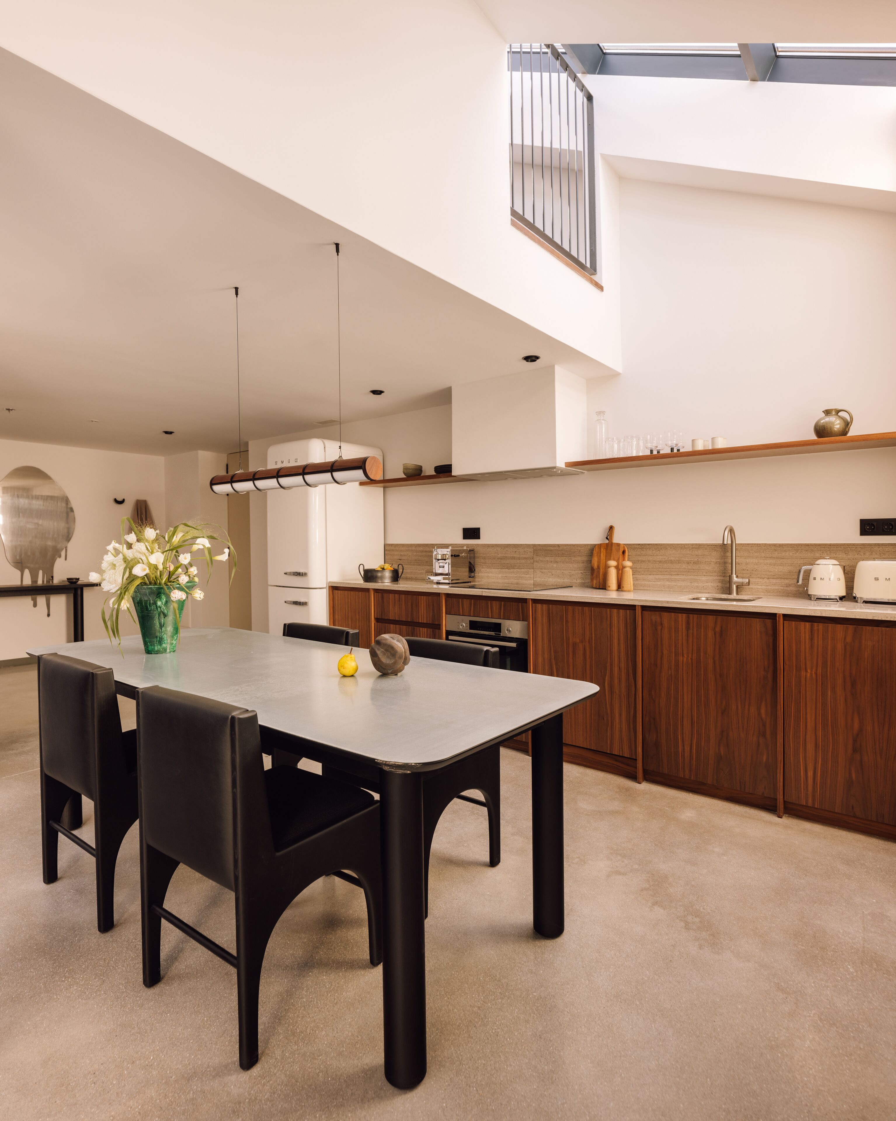 A modern kitchen with a dining area, featuring a large island, wooden cabinets, and a skylight.