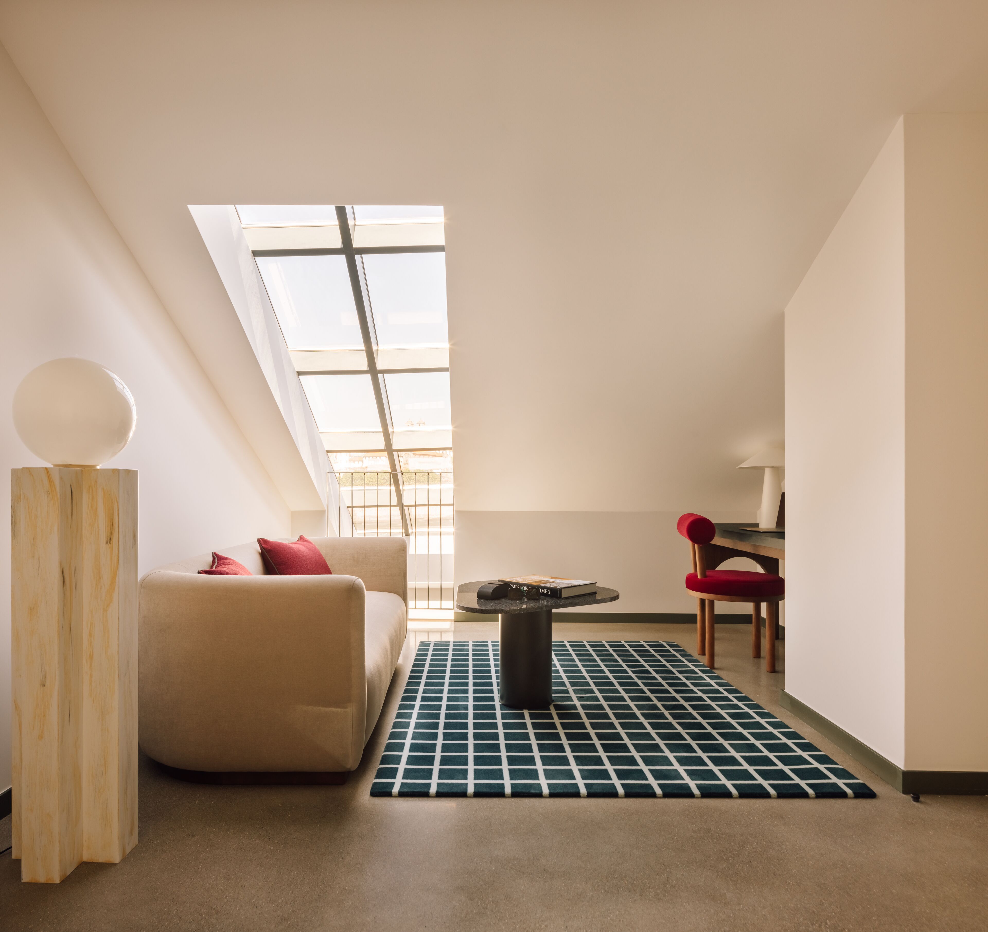 A modern, well-lit room with a skylight, a sofa, a table, and a chair.