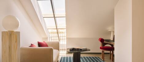 A modern, well-lit room with a skylight, a sofa, a table, and a chair.