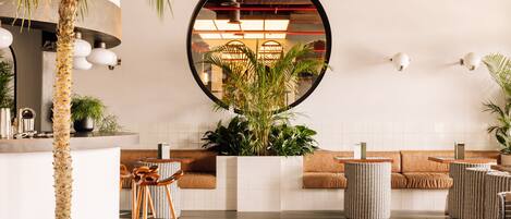 Un interior moderno con una zona de estar central, un espejo grande y plantas en macetas.