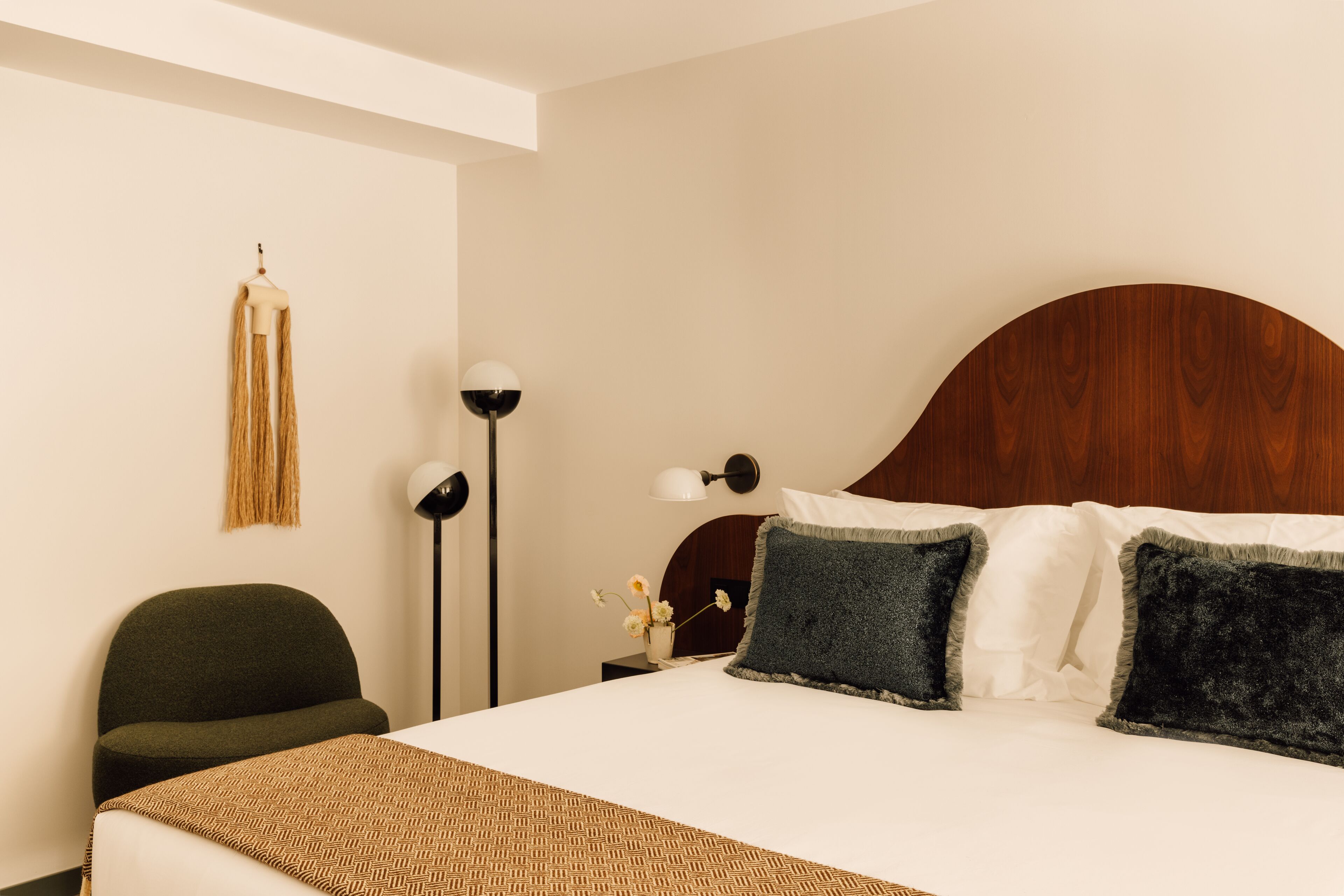 Ein ordentlich eingerichtetes Hotelzimmer mit einem großen Bett, einem Sessel, einer Lampe und einer Wandleuchte.