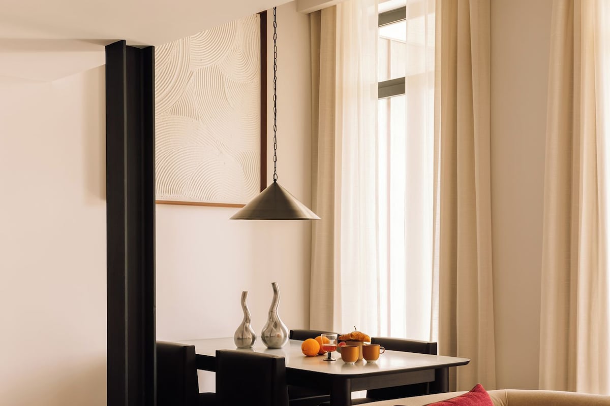 A modern living room with a sofa, a dining table with fruit, and a pendant light.