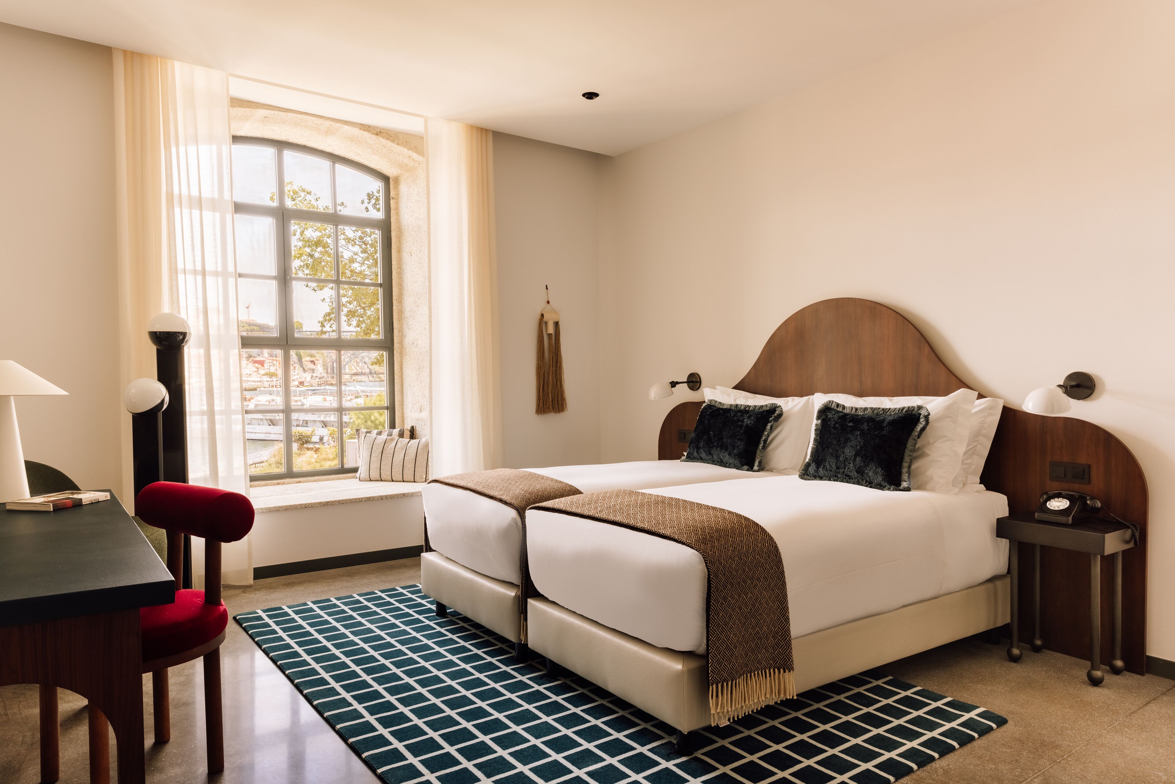Un dormitorio ordenado con cama, mesitas de noche, escritorio y silla.