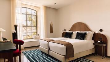 Un dormitorio ordenado con cama, mesitas de noche, escritorio y silla.