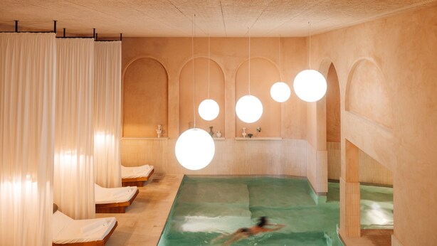 A spa room with a large pool, wooden loungers, and a person swimming. - The Rebello Hotel & Spa (Vila Nova de Gaia)