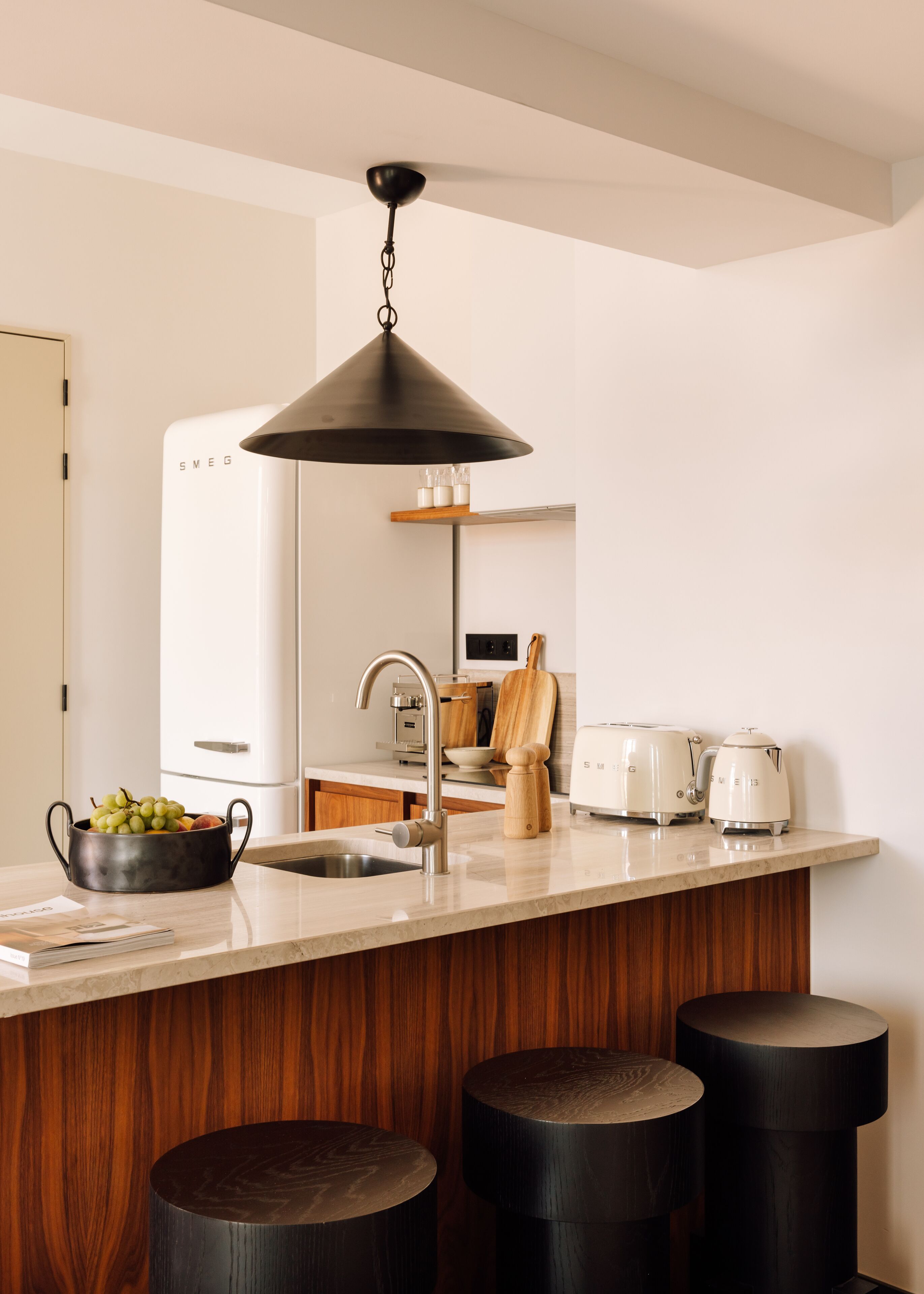 Una cucina moderna con isola centrale, elettrodomestici in acciaio inossidabile e lampadario a sospensione.