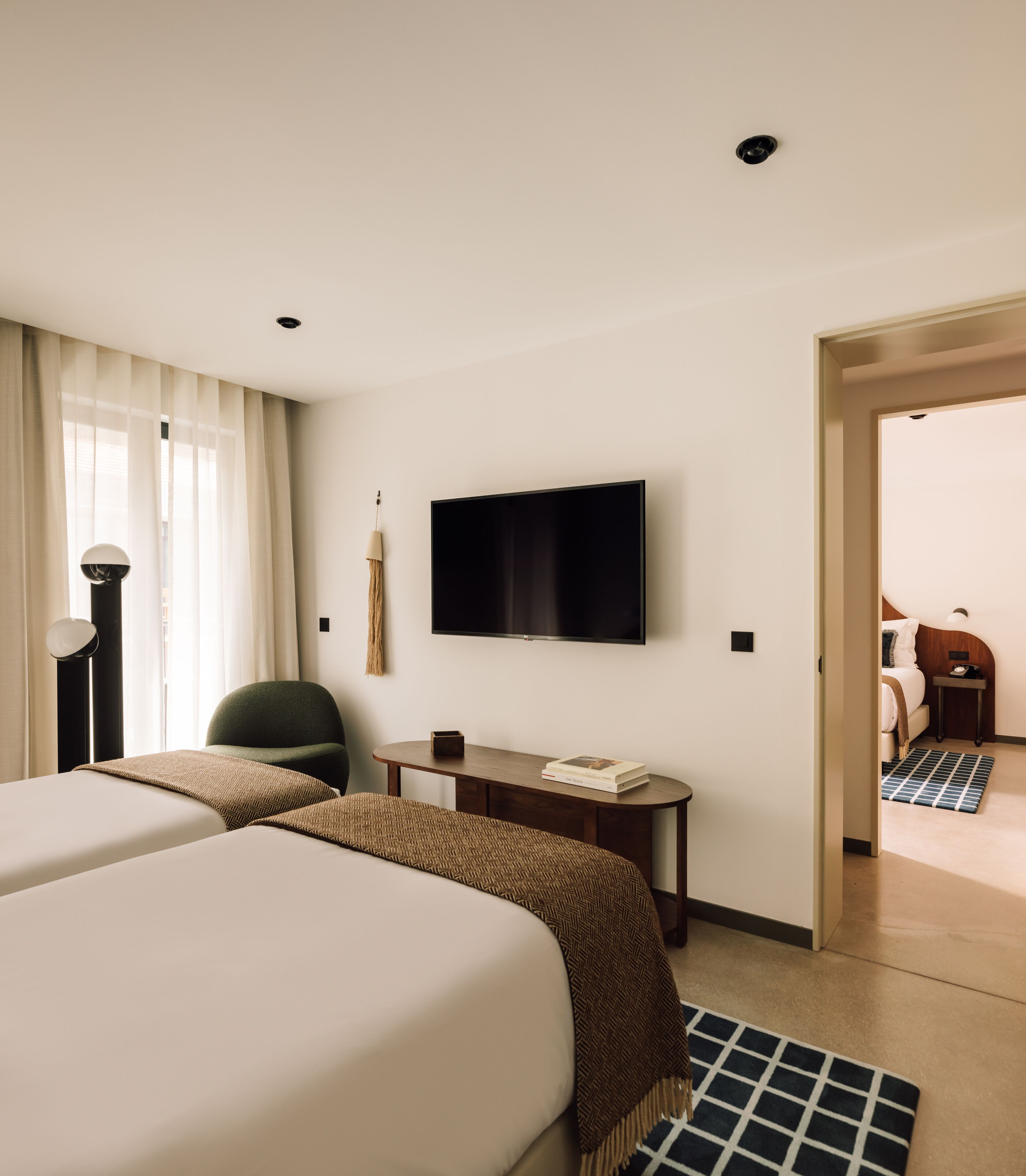 A hotel room with two beds, a flat-screen TV, a desk, and a chair.