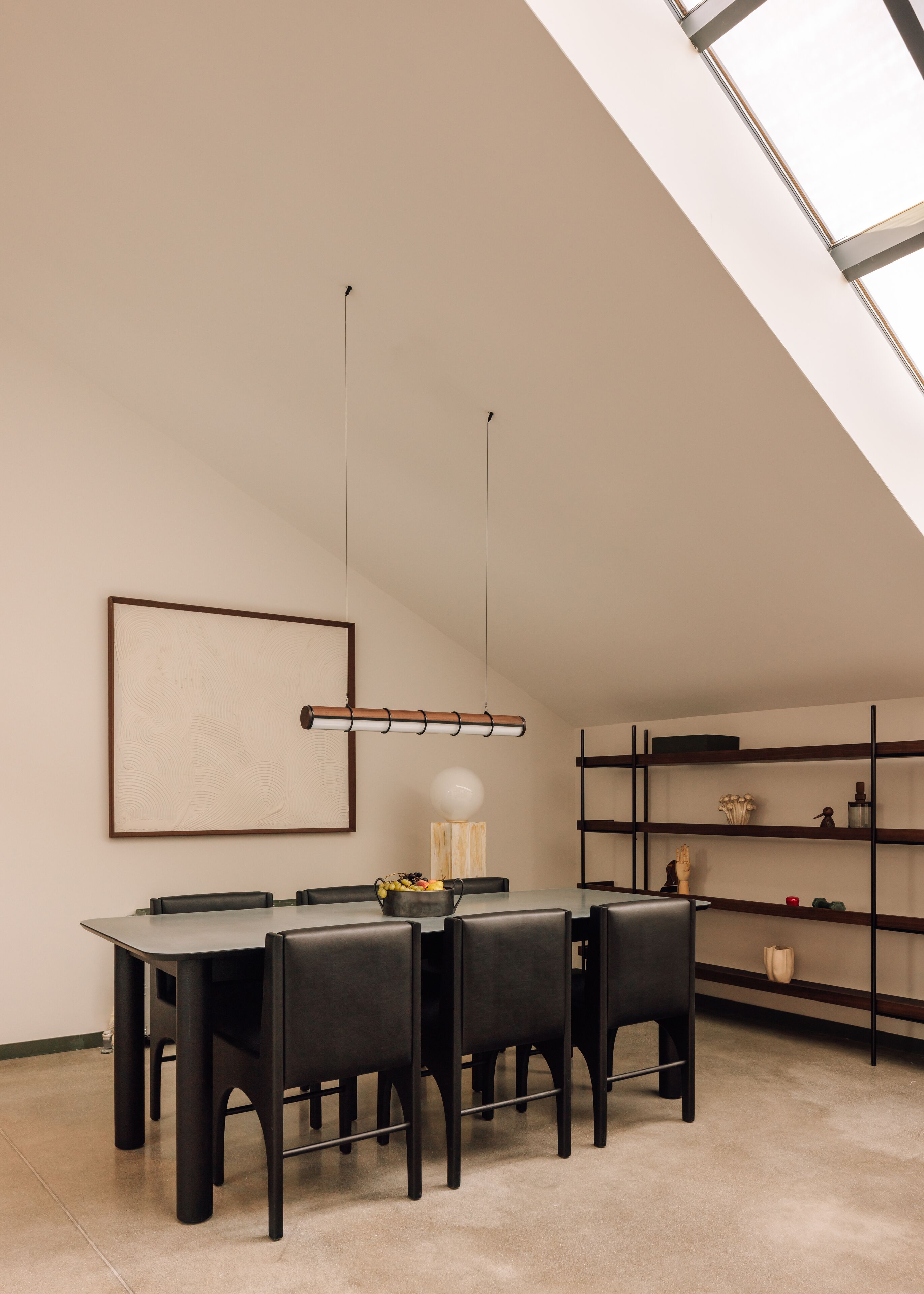 Un comedor moderno con una mesa, sillas, una lámpara colgante y una estantería.