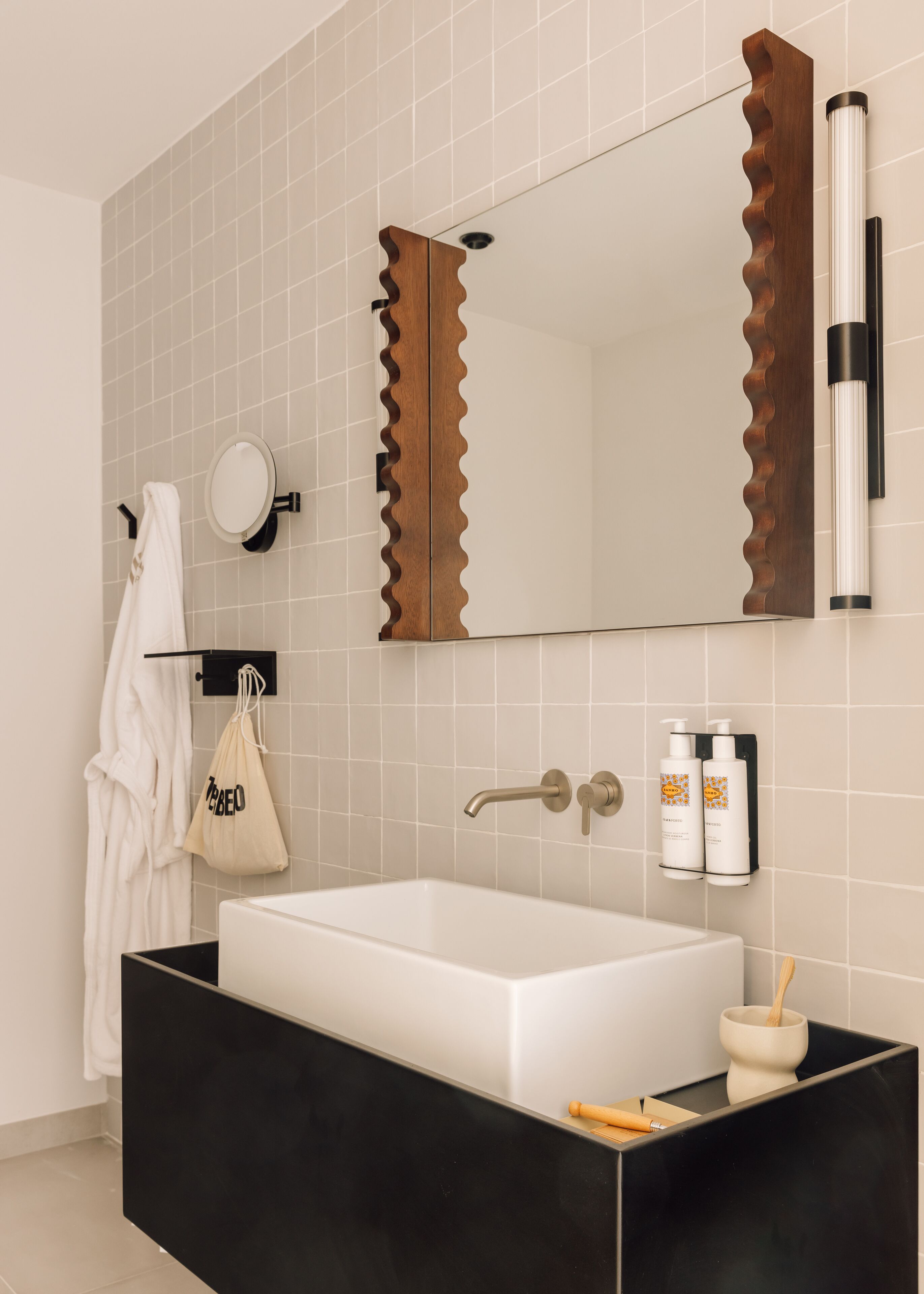 A modern bathroom with a large mirror, a white sink, and a black vanity.