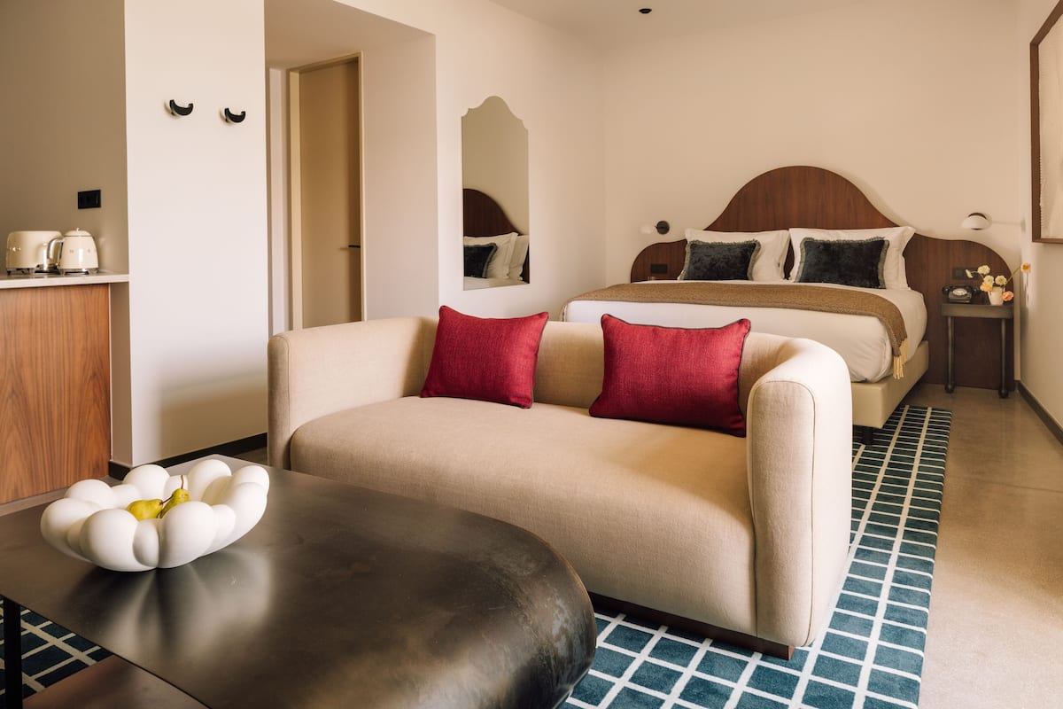 A hotel room with a bed, a sofa, a coffee table, and a nightstand.
