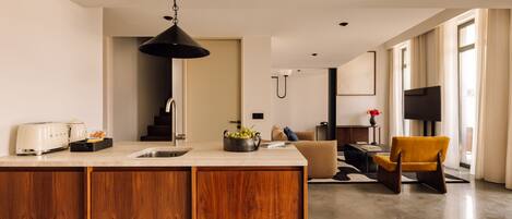 Una cocina moderna con armarios de madera, una isla integrada y una zona de comedor con una silla amarilla.