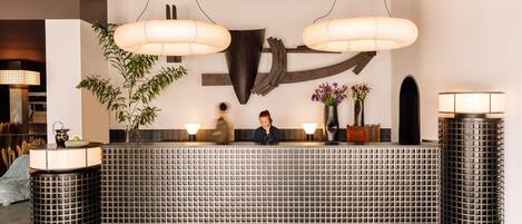 A reception desk with a modern design, featuring a grid-patterned counter and two large pendant lights.