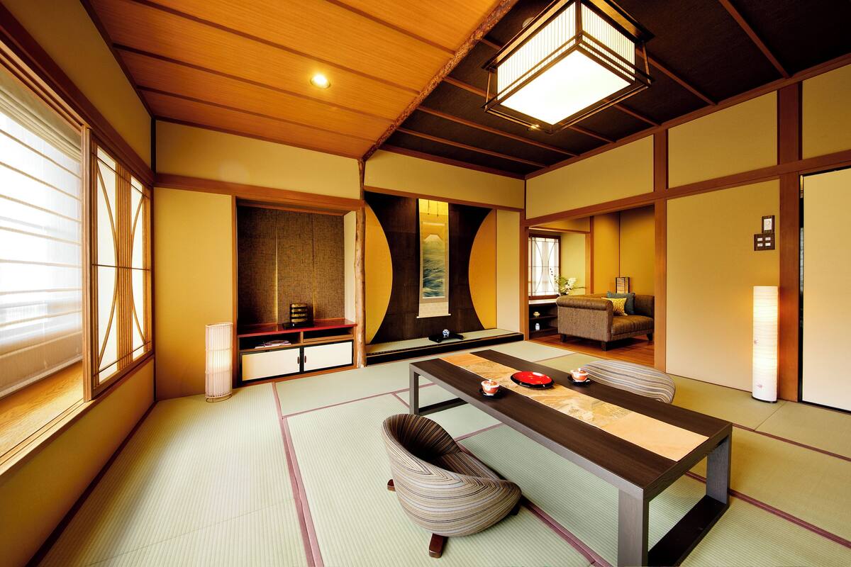 A traditional Japanese room with tatami flooring, a low table, cushions, and sliding doors.
