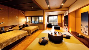 Een traditionele Japanse hotelkamer met tatami vloeren, twee bedden, een zithoek met tatami matten en een balkon met uitzicht.