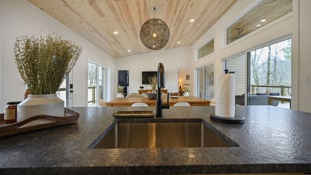 A modern kitchen with a granite countertop, a stainless steel sink, and a wooden ceiling. - Cabin w/ Heated Pool, Pickleball Court Access & Spacious Deck (Broken Bow)
