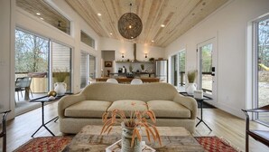 A modern living room with a beige sofa, a coffee table with a vase, and a wooden ceiling. - Cabin w/ Heated Pool, Pickleball Court Access & Spacious Deck (Broken Bow)