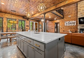 Une cuisine spacieuse dotée d’un grand îlot central, d’un plafond en bois et de luminaires suspendus modernes.