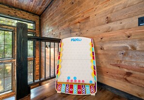 Un plateau de jeu intitulé « PLINKO » est placé contre un mur en bois, près d’une fenêtre.