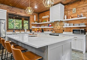 Une cuisine moderne dotée d’un grand îlot central, de tabourets de bar et d’éléments décoratifs en bois.