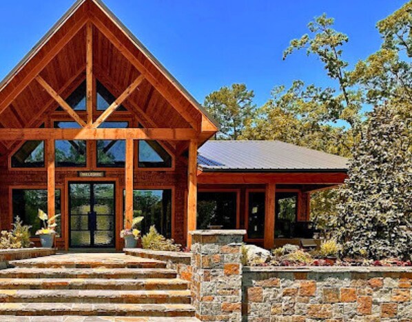 A wooden lodge with a steeply pitched roof, large windows, and a stone staircase leading to the entrance. - Lone Star Lodge Cabin in Broken Bow (Broken Bow)