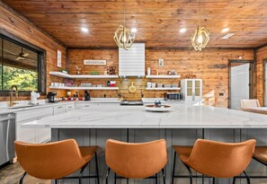 Een moderne keuken met een ruim eiland, houten details en hanglampen.