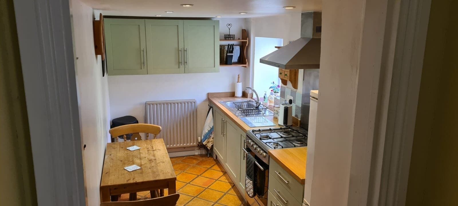 Une cuisine de taille réduite, avec une table et des chaises en bois, une cuisinière à gaz et un évier.