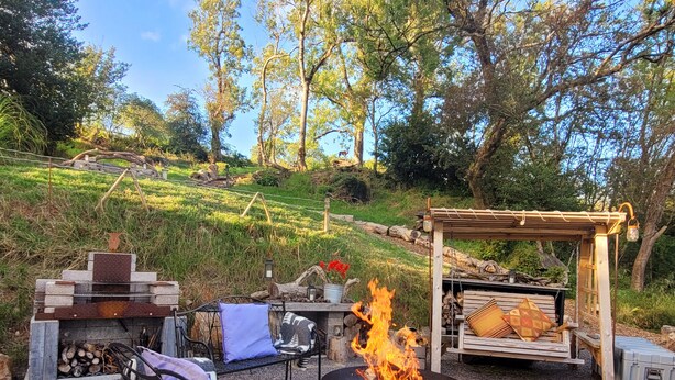 An outdoor seating area with a fire pit, benches, and a pergola.