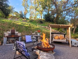 An outdoor seating area with a fire pit, benches, and a pergola.