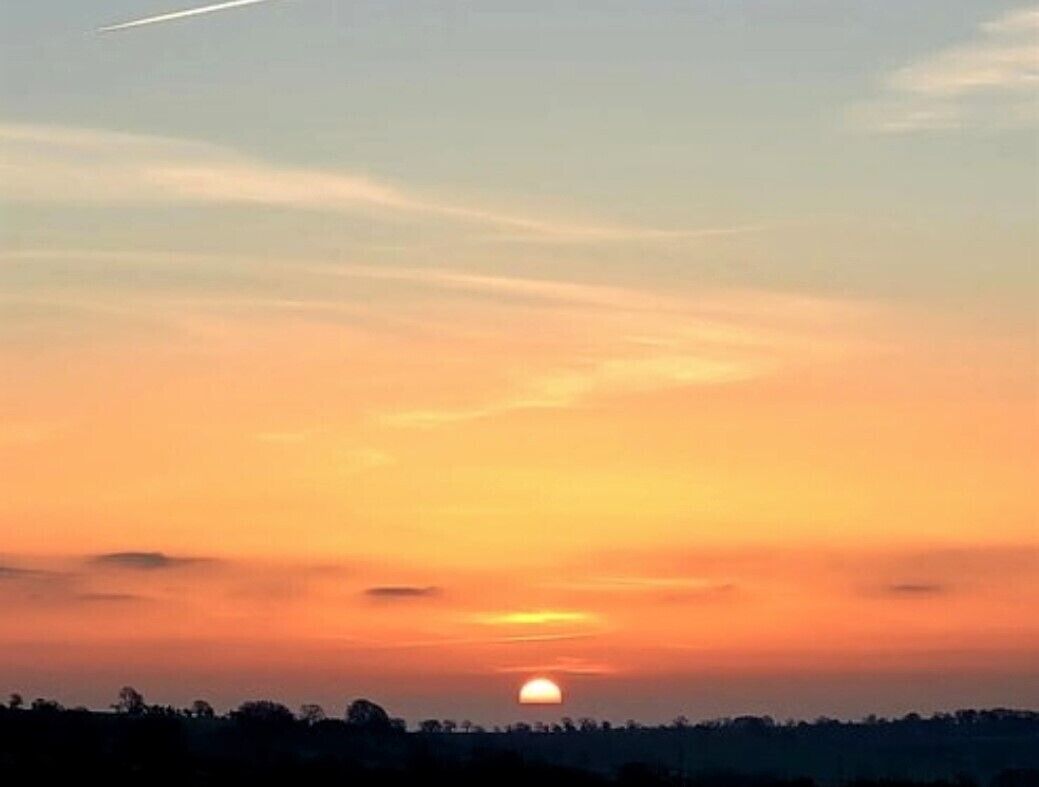 Un coucher de soleil avec un ciel dégagé et une ligne d’horizon bien visible.