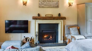 A cozy living room with a fireplace, a flat-screen TV, and a comfortable seating area.