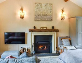 A cozy living room with a fireplace, a flat-screen TV, and a comfortable seating area.