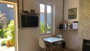 Une pièce comprenant une table et des chaises, un téléviseur fixé au mur, une cheminée et une fenêtre donnant sur un paysage verdoyant.