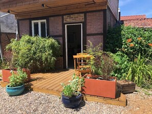 A wooden deck with potted plants and a wooden bench. - the watering hole room (Bergicourt)