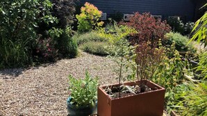 Un jardin avec différentes espèces de plantes et une terrasse en bois.