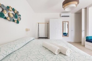 A modern hotel room with a large bed, a wardrobe, a mirror, and an air conditioning unit. - Villa Briosa: Vacation Home with Ocean Views in Salento (Puglia)