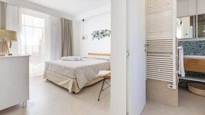 Ein modernes Schlafzimmer mit Bett, Nachttisch und Blick ins Badezimmer.