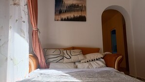 Un dormitori amb llit, almoines, un quadre i una porta apuntada.