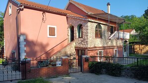 Una casa de dues plantes amb teulada de rajola vermella, façana de pedra i entrada de maó.