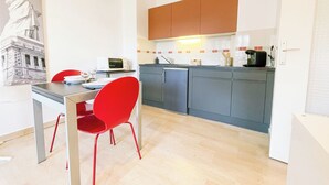 Une cuisine compacte avec un coin repas, comprenant une chaise rouge, un four à micro-ondes et un évier.