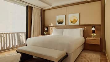 A hotel room with a large bed, a bench, two bedside tables with lamps, and artwork on the wall.