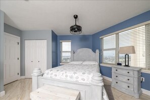 A bedroom with a bed, a nightstand, a dresser, a ceiling fan, and a window with blinds.
