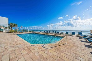 A pool area with a clear view of the ocean, a flag, and a sign indicating the pool depth.