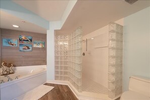 A bathroom with a glass shower enclosure, a bathtub, and a toilet.