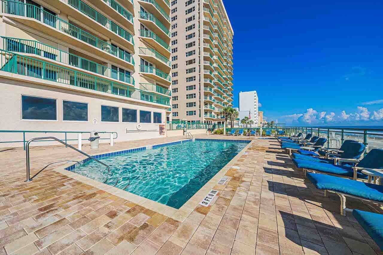 A swimming pool with lounge chairs and a view of a tall building.