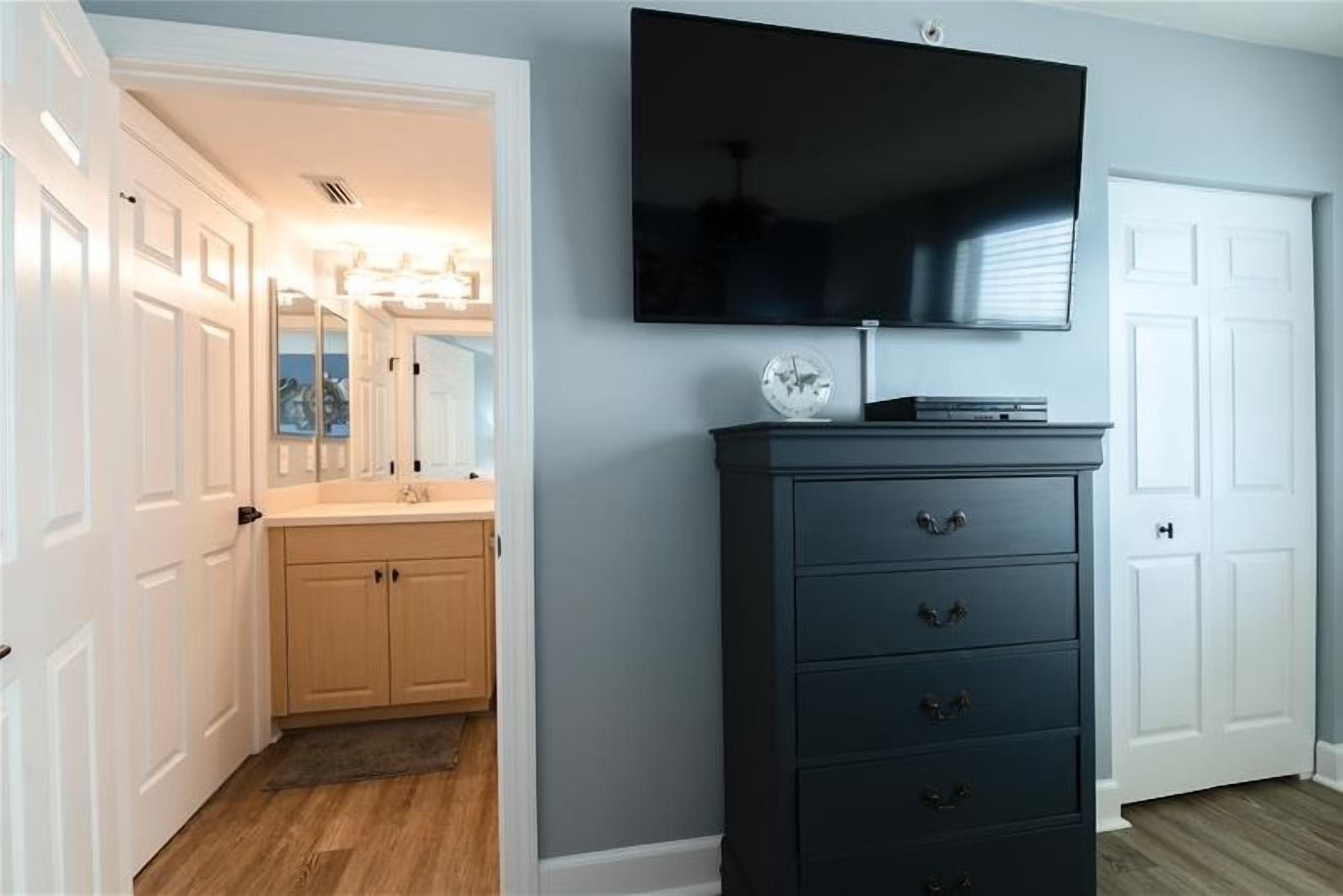 Una habitación con un aparador azul oscuro, un televisor de pantalla plana montado encima y una puerta blanca a la derecha.