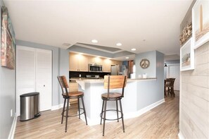 A modern kitchen with white cabinets, a central island, and two bar stools.
