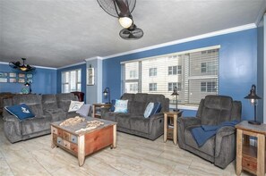 A living room with two grey sofas, a wooden coffee table, and a ceiling fan.