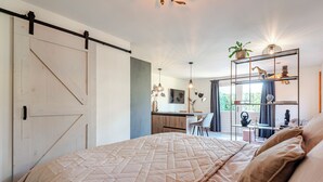 Un dormitorio con una cama grande, un escritorio y una estantería con objetos decorativos.